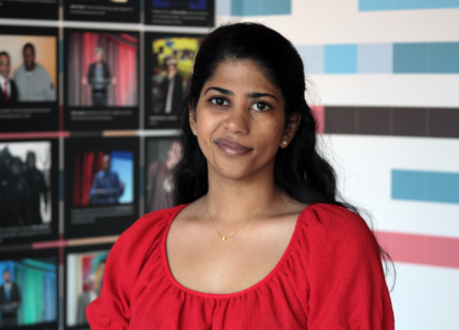 Picture of with dark hair and brown eyes wearing red top smiling at camera