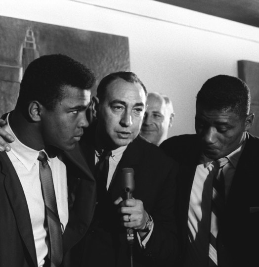 Muhammad and another man in a suit with a man and a microphone