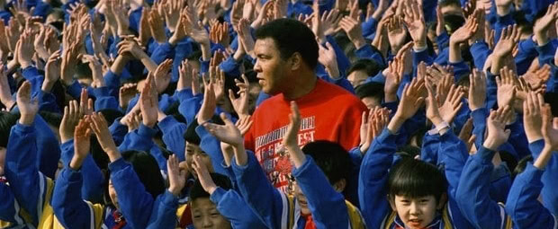 Muhammad Ali stands in a crowd of young, Asian children in matching outfits