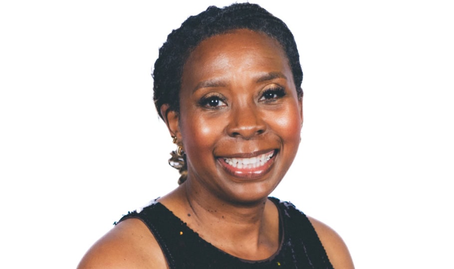 Photo of woman with short hair wearing black, shining dress smiling at camera