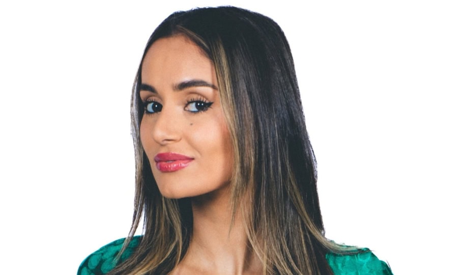 Photo of woman with long dark hair wearing green dress posing for camera