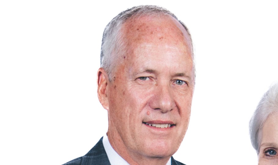 Photo of man with short white hair wearing gray suit smiling at camera