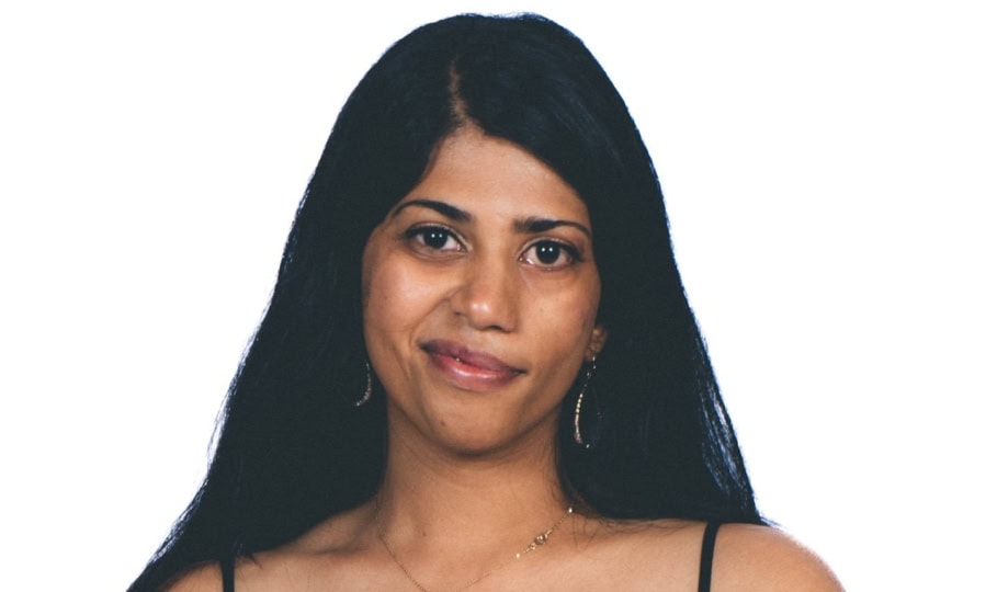 Woman with long black hair wearing black dress smiling at camera