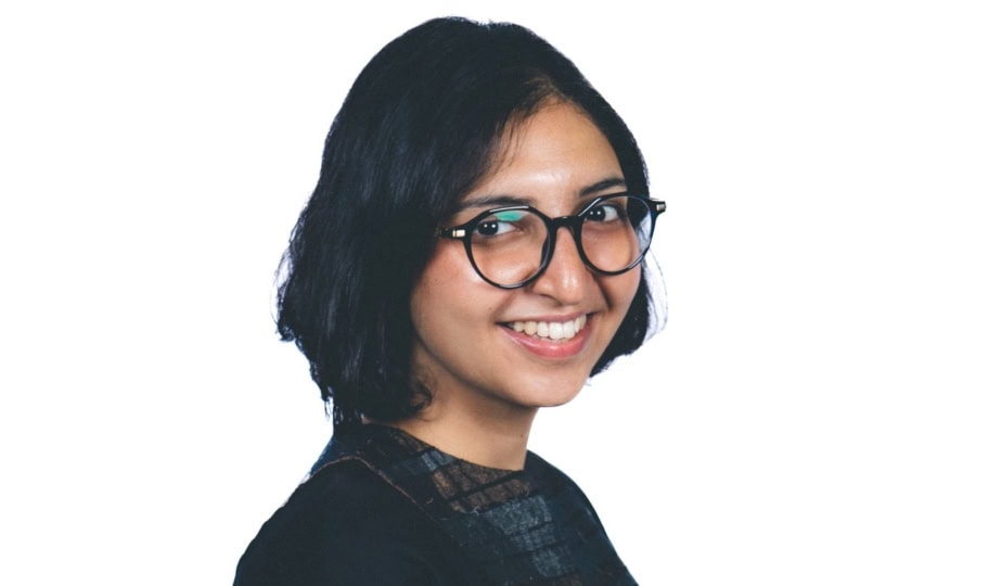 Photo of woman with short dark hair wearing glasses and wearing dark dress posing for camera