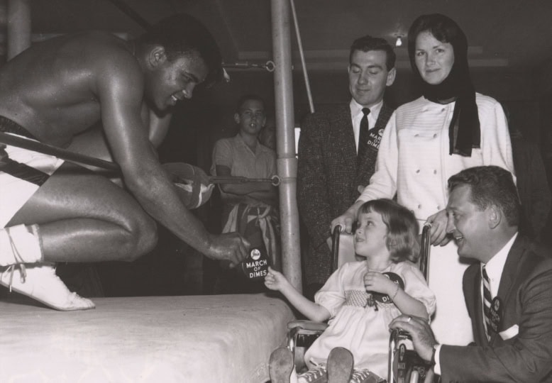 Muhammad Ali leans out of boxing ring to greet young girl in wheelchair