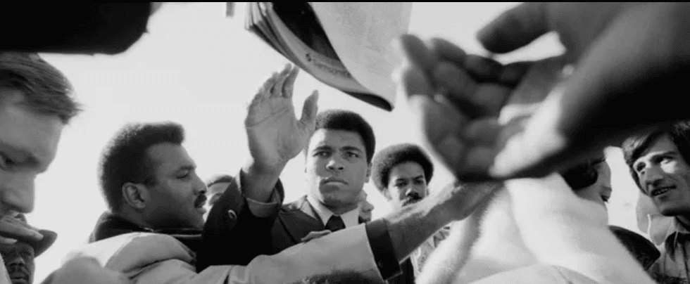 Muhammad Ali reaches through a crowd
