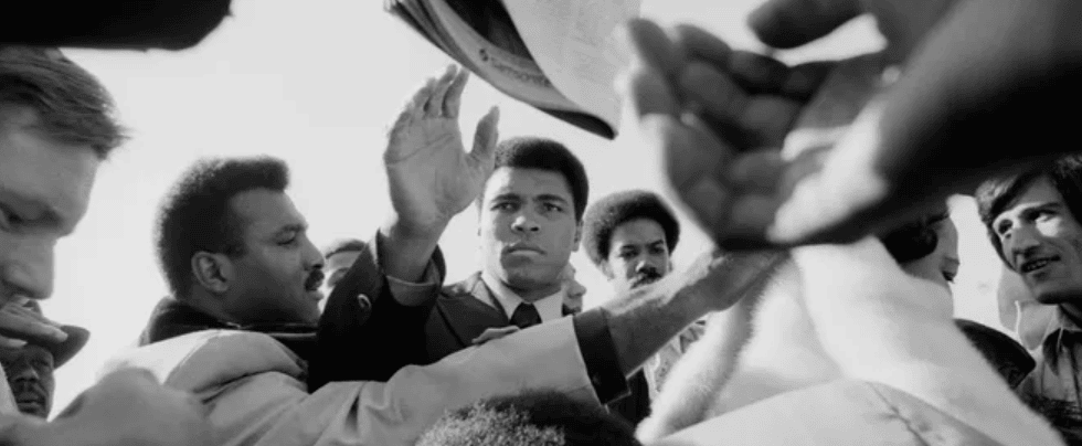 Muhammad Ali reaches through a crowd