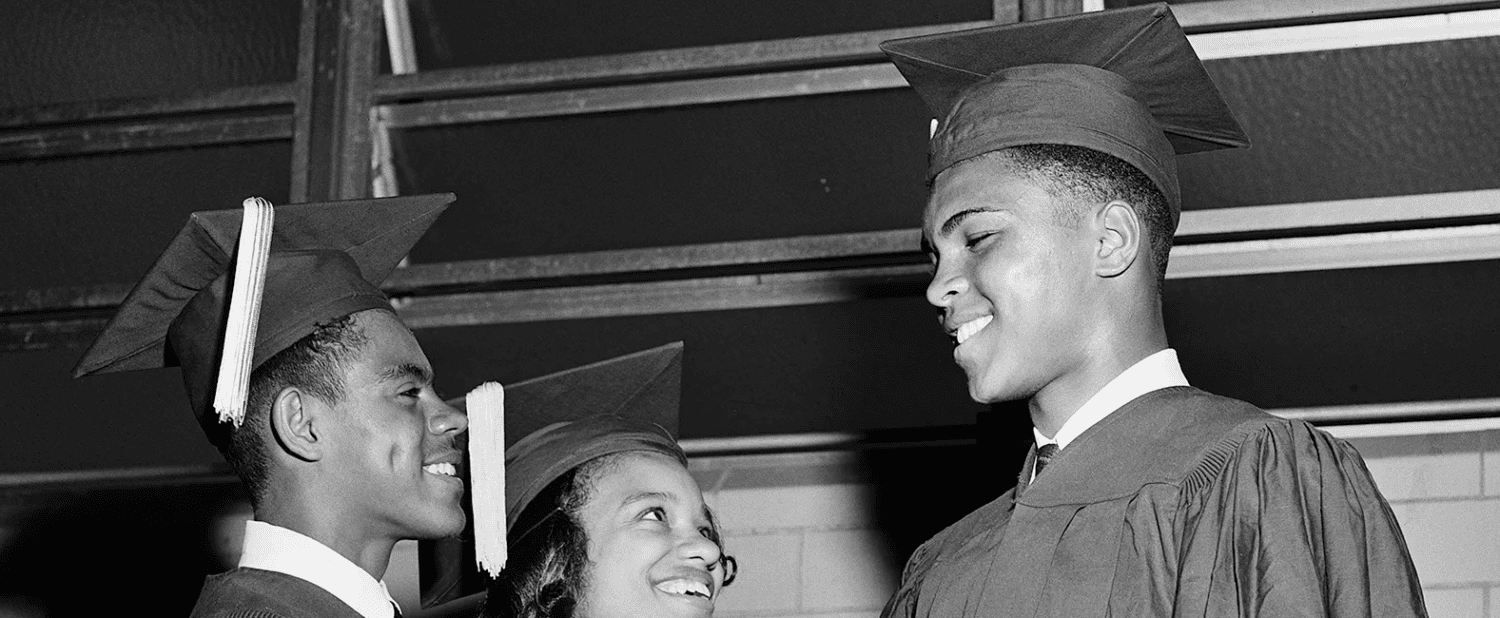 A young Muhammad Ali in graduation regalia shaking hand with fellow student.