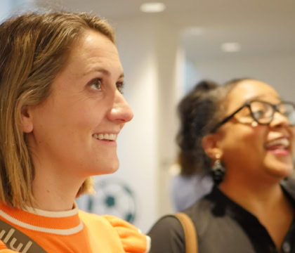 Photo of two women looking at art exhibition and smiling