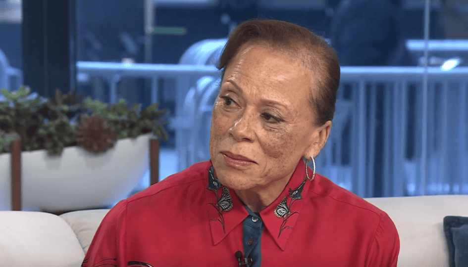 Woman with short brown hair wearing red shirt sitting in TV studio