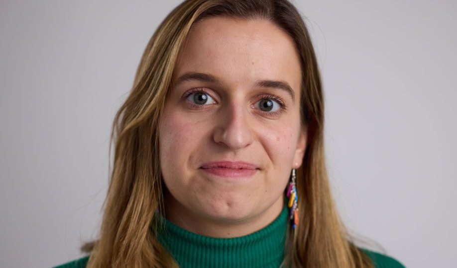 Photo of woman with long blond hair wearing green sweater smiling at camera