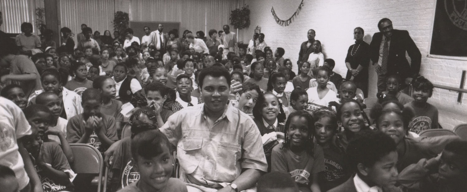 Muhammad Ali sits in a room with hundreds of school aged children at a charity event