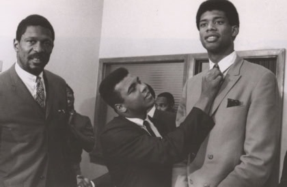 Black and white photo of Muhammad Ali adjusting tie on another man's suit