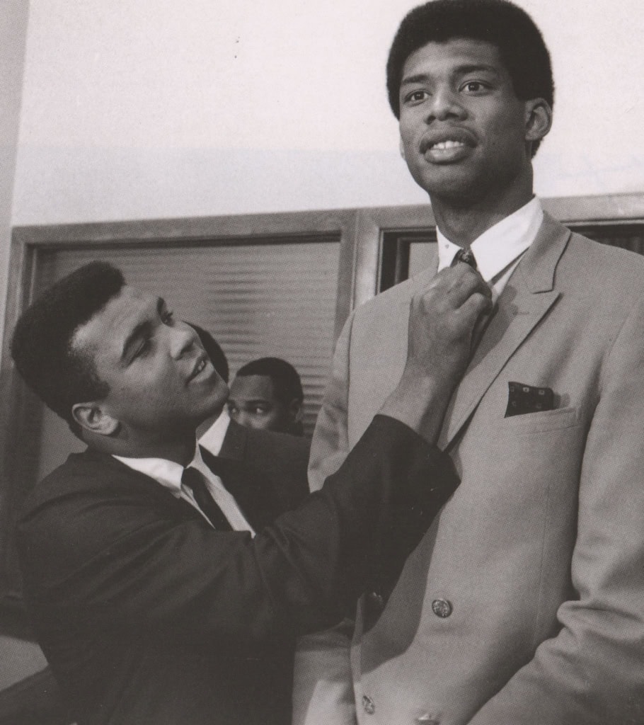 Black and white photo of Muhammad Ali adjusting tie on another man's suit