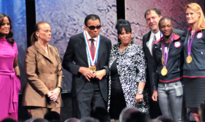 Muhammad Ali standing on stage with seven people, receiving an award.