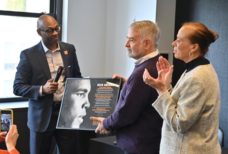 Group of people holding up framed photo of Muhammad Ali's face