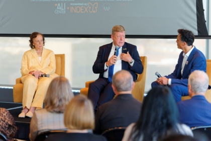 Three people sitting on stage talking as people look on